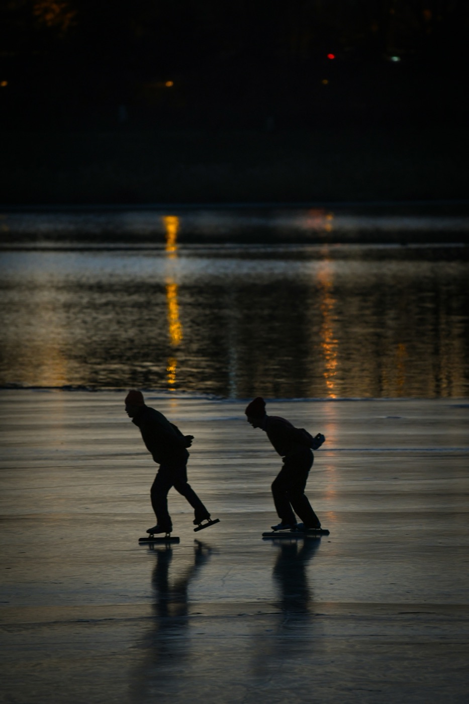 Twee schaatsers in de avondschemering op natuurijs