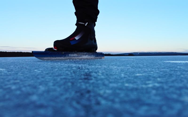 Schaatsijzer op helder, blauw natuurijs onder een heldere lucht