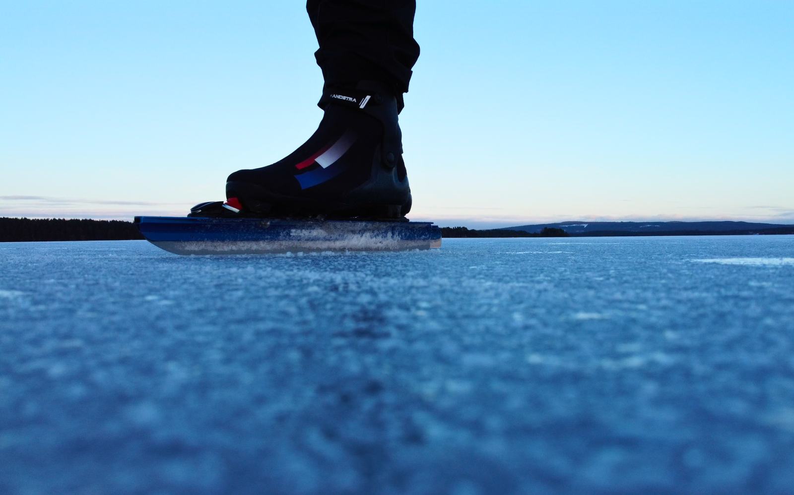 Schaatsijzer op helder, blauw natuurijs onder een heldere lucht