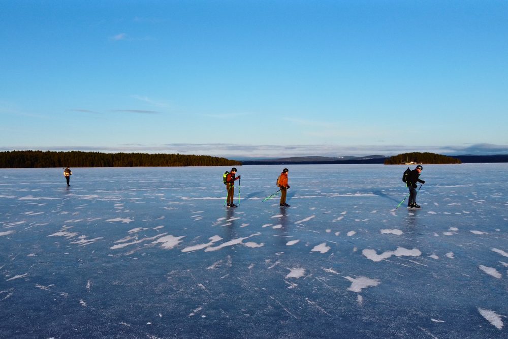 Groepje schaatsers op het bevroren meer bij Falun onder een blauwe lucht