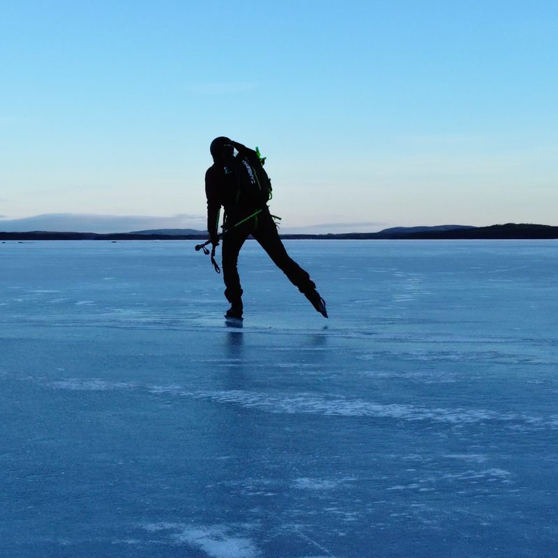 Toerschaatser met rugzak op helder natuurijs bij Falun, onder een heldere lucht