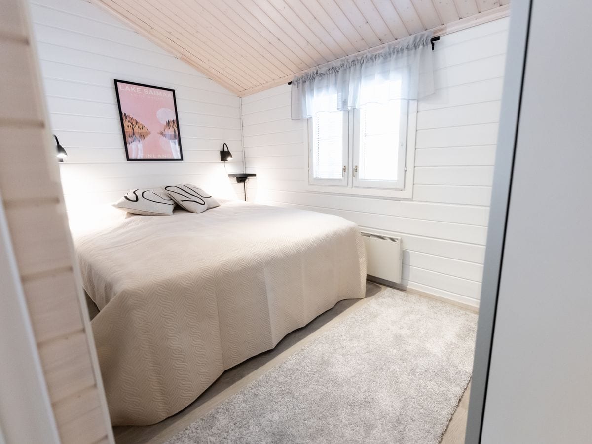 Slaapkamer met tweepersoonsbed onder een schuin houten plafond
