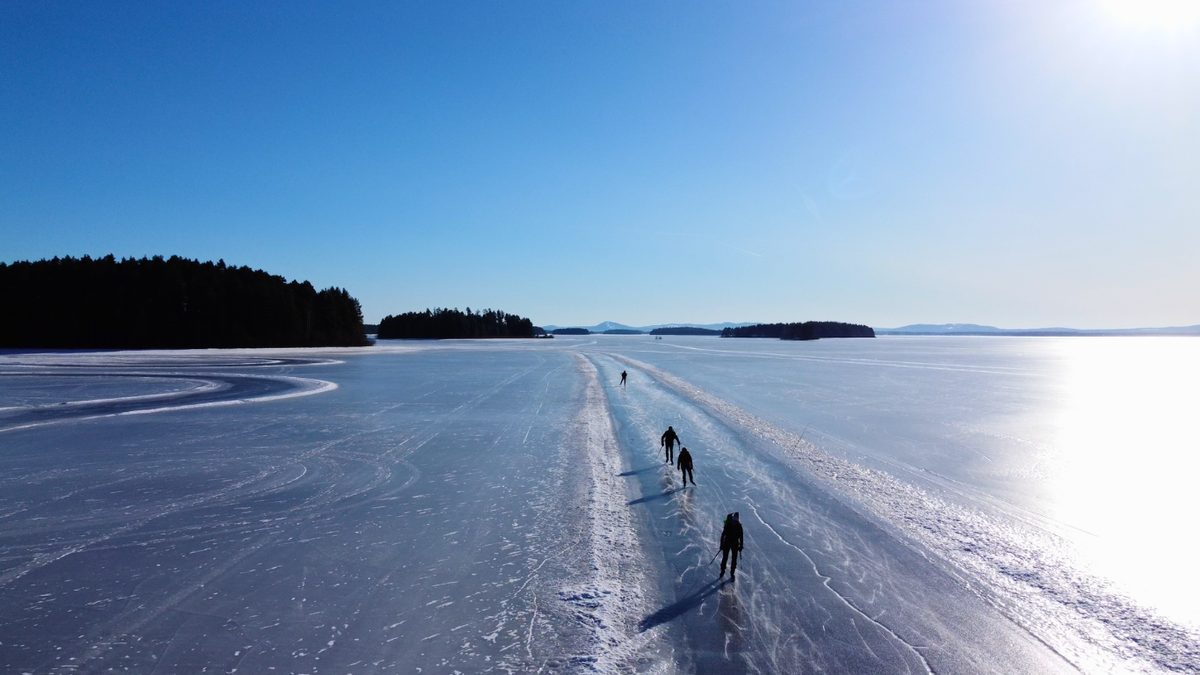 Schaatsers op een geveegde baan met sneeuwranden over een bevroren Zweeds meer
