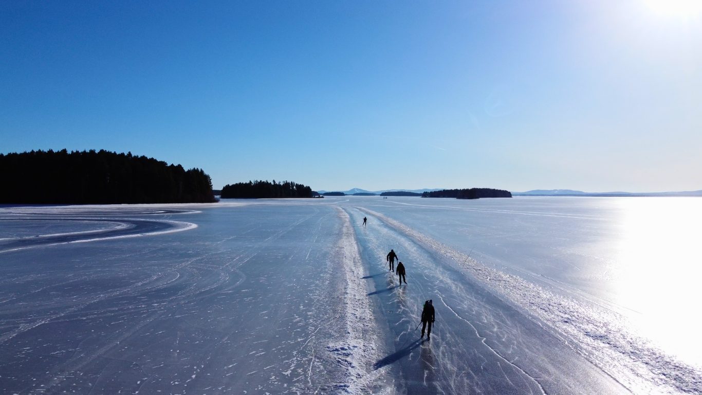 Schaatsers op een geveegde baan met sneeuwranden over een bevroren Zweeds meer