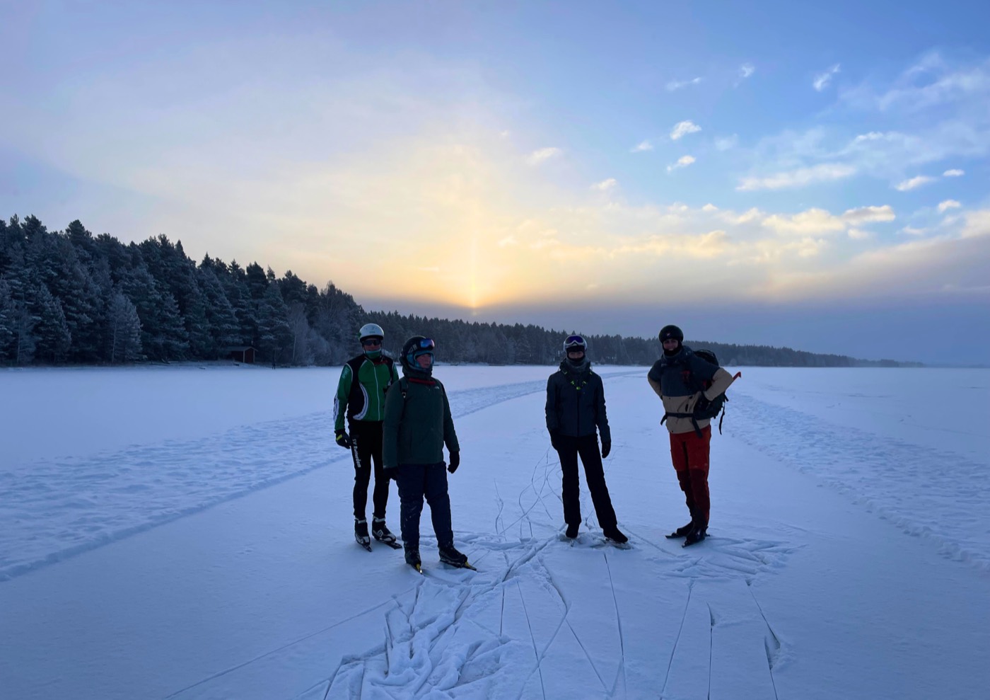 Schaatsers staan stil op het bevroren meer bij zonsopkomst