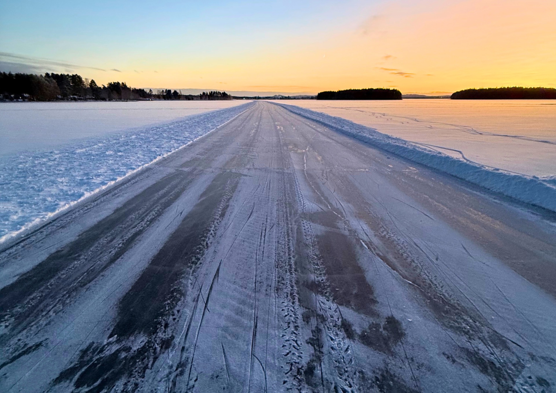 Geveegde schaatsbaan over een bevroren meer bij zonsondergang
