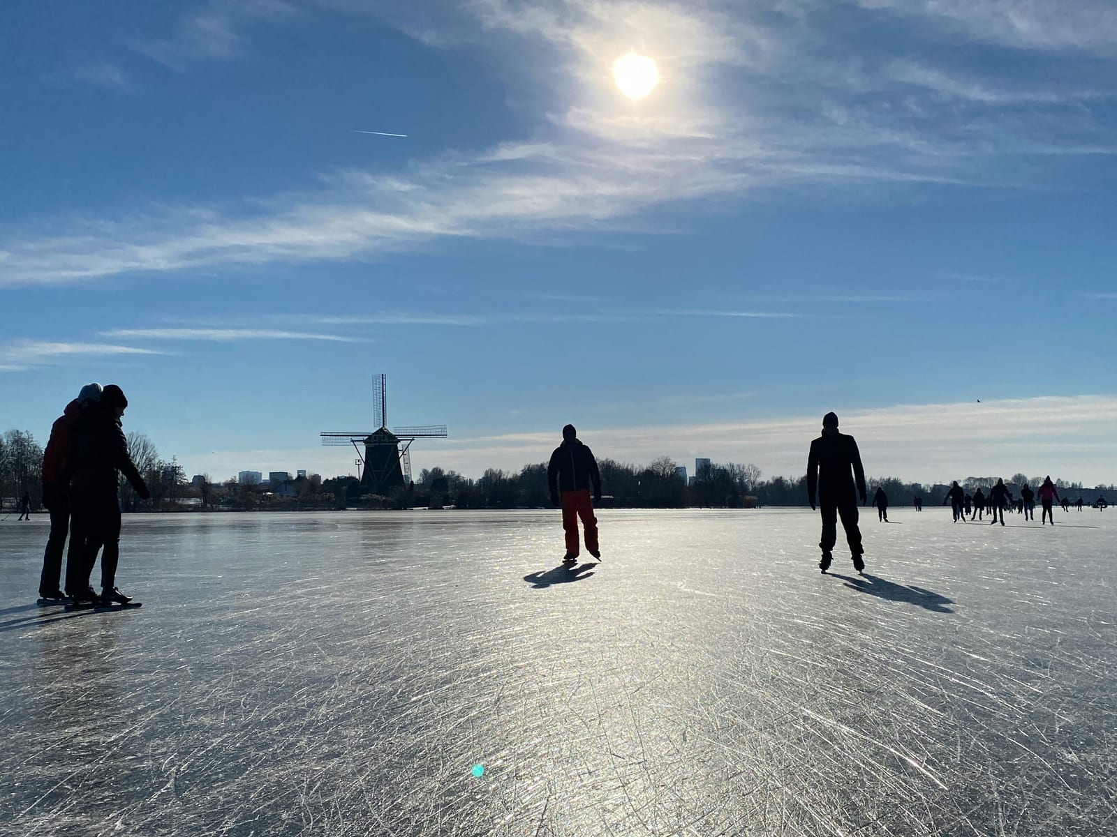 Schaatsers op Nederlands natuurijs met een molen op de achtergrond