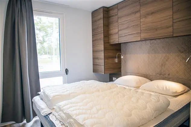 Slaapkamer met tweepersoonsbed en leeslampjes, met houten kasten boven het bed