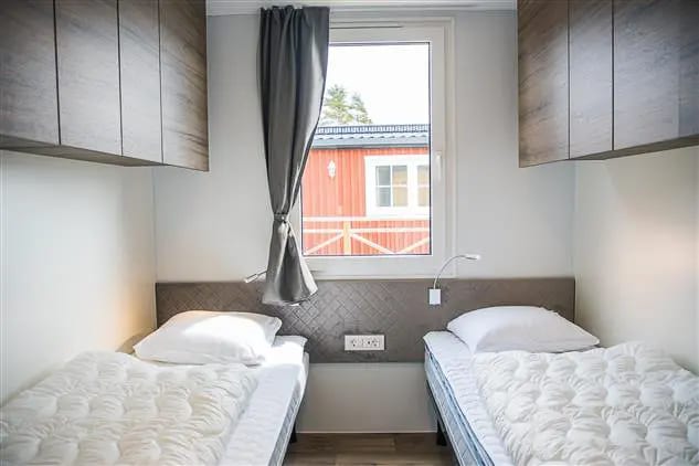 Slaapkamer met twee eenpersoonsbedden aan weerszijden van het raam
