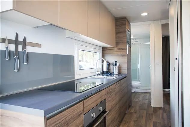 Keuken met kookplaat, oven en spoelbak, met een doorkijk naar de badkamer