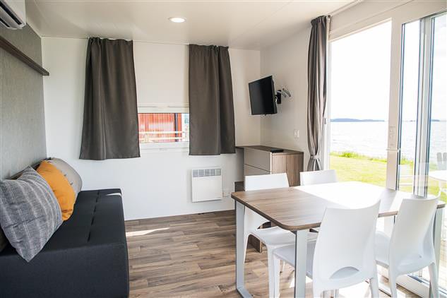 Woonkamer met bank, eettafel en glazen deuren met uitzicht op het meer