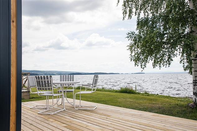 Terras met witte tuinstoelen en een tafel, met uitzicht over het meer