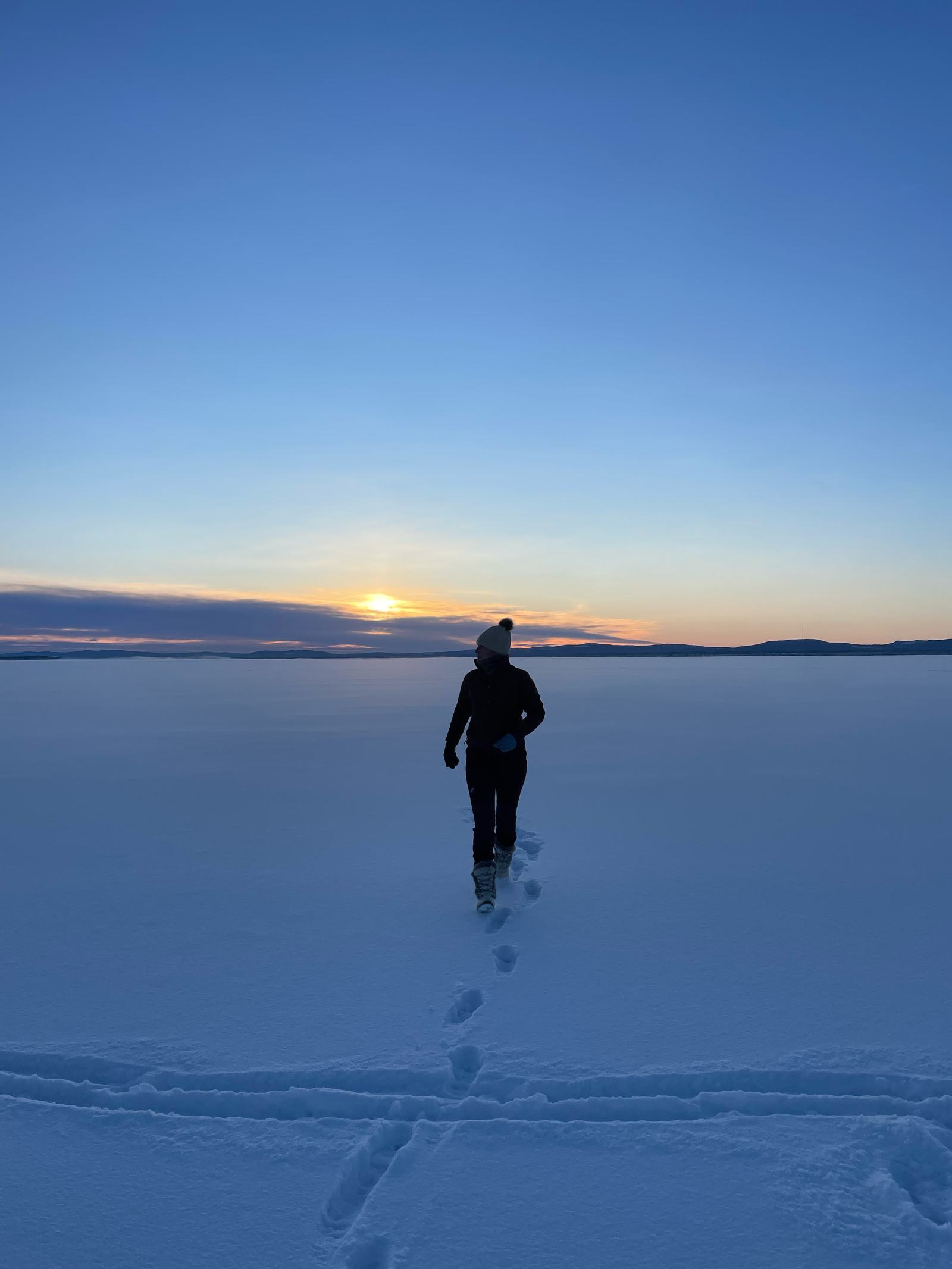 Schaatser op een besneeuwd meer bij zonsondergang