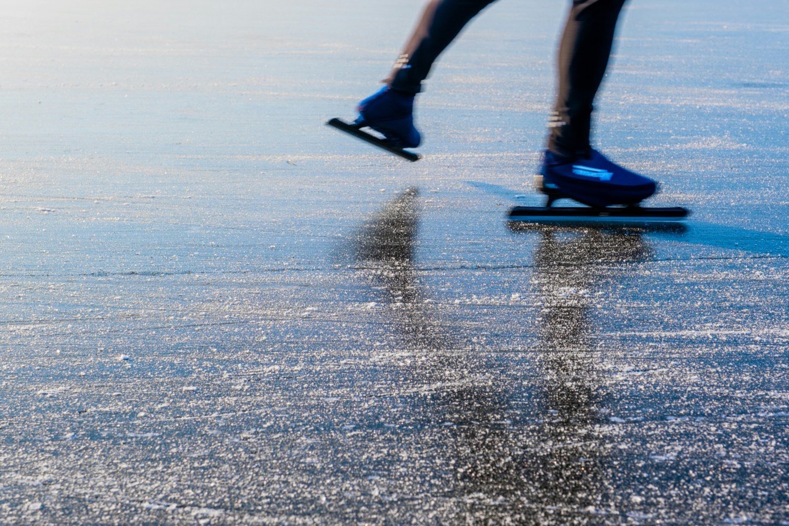 Close-up van schaatsijzers en ijsspatten tijdens het schaatsen op het rechte stuk