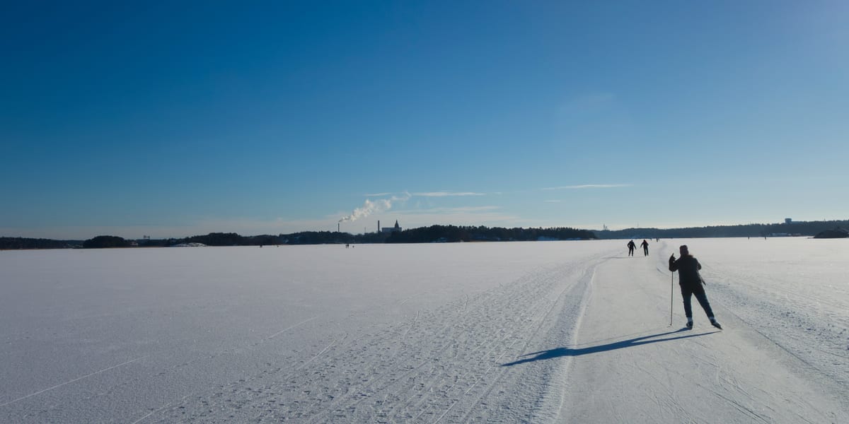 Schaatser op een lang geveegde natuurijsbaan over een besneeuwd meer