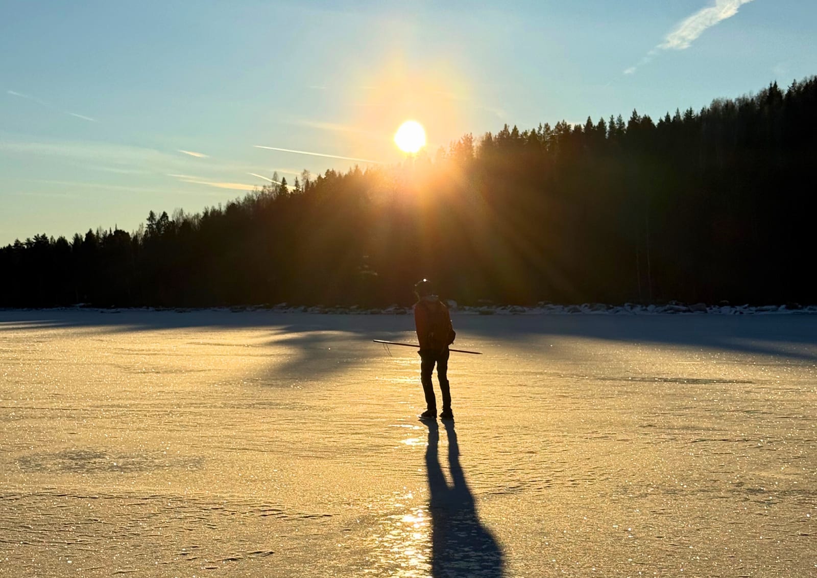 Schaatser in tegenlicht op een bevroren meer bij lage zon