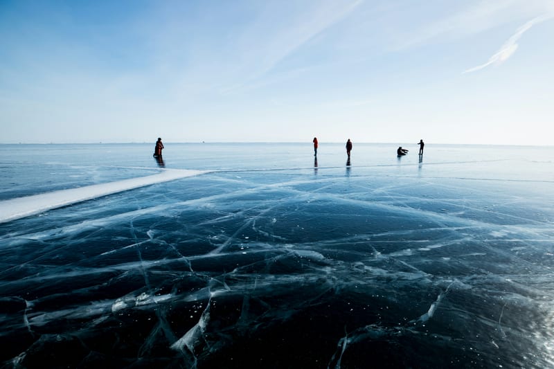 Schaatsers verspreid over glad zwart natuurijs